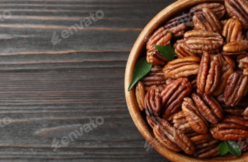 Preview: Dish with shelled pecan nuts on wooden background, top view. Space for text