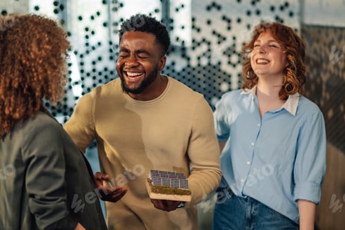 Preview: Happy interracial staff with solar panel prototype having fun at office