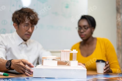 Preview: Architect designer explaining house model to client in the office