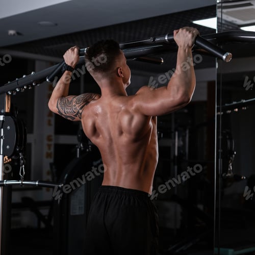 Preview: strong handsome man athlete with a muscular naked back pulls up in the sports gym