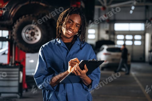 Preview: Taking notes into notepad. Male mechanic is with car in garage