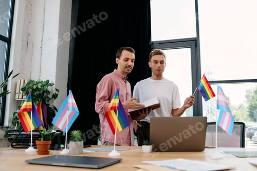 Preview: A vibrant workspace showcasing a handsome gay couple discussing ideas with pride flags around