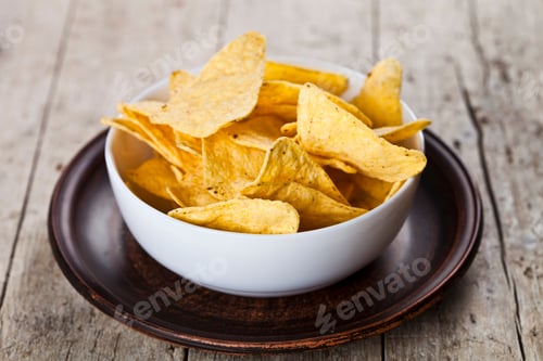 Preview: Mexican nachos chips in white bowl on brown ceramic plate.