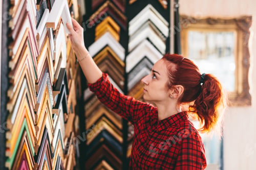 Preview: Woman shop assistant in face mask working in picture frames store