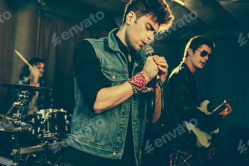 Preview: selective focus of fashionable man singing song near rock band