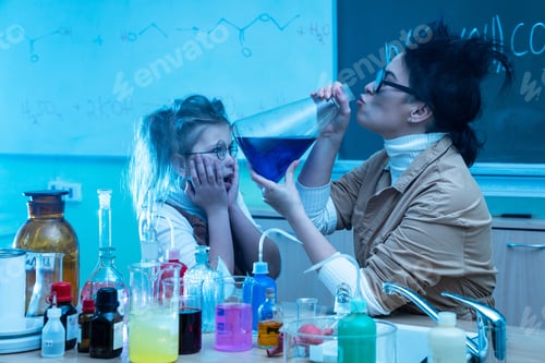 Preview: Teacher and little girl during chemistry lesson mixing chemicals in a laboratory