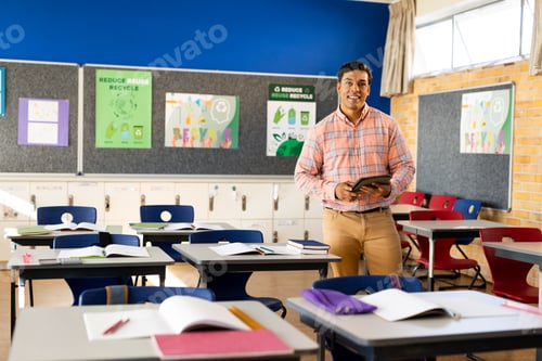 Visualização: Retrato de professor masculino birracial feliz com tablet na sala de aula do ensino fundamental, espaço de cópia