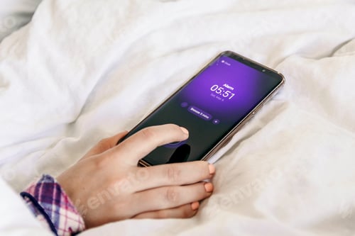 Preview: Close-up image of hand snoozing alarm clock on mobile phone. Bed, morning, waking up.