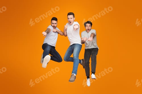 Visualização: Three men jumping joyfully on orange backdrop
