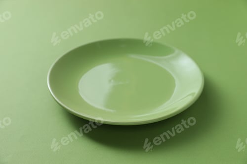 Preview: One empty plate on green background, closeup