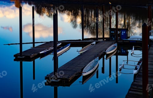 Preview: Beautiful scenery of a dock on the side of a river with mirror reflection of the sky on water