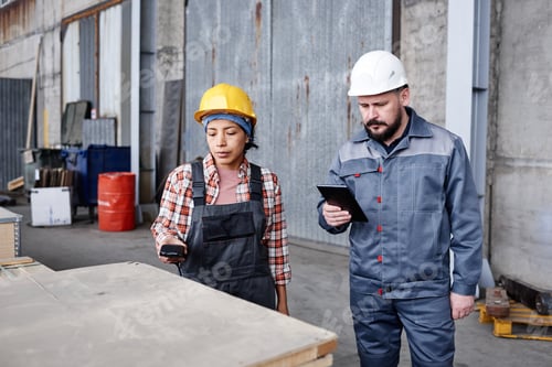 Preview: Young female engineer and foreman checking barcodes on boxes with spare parts