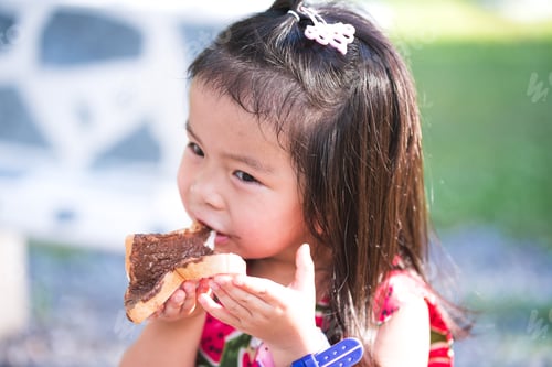 Preview: Adorable kid enjoying delicious chocolate-covered bread. Hungry children eating snacks at park.