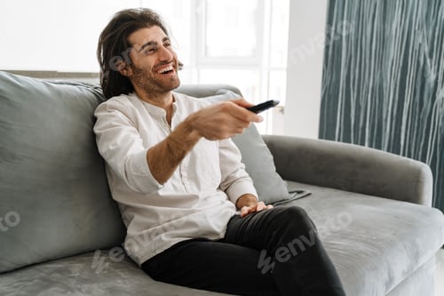 Preview: Happy young man holding TV remote