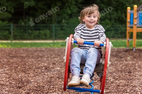 Preview: Toddler boy on swing on playground, happy child swaying outdoor in the park in summer.