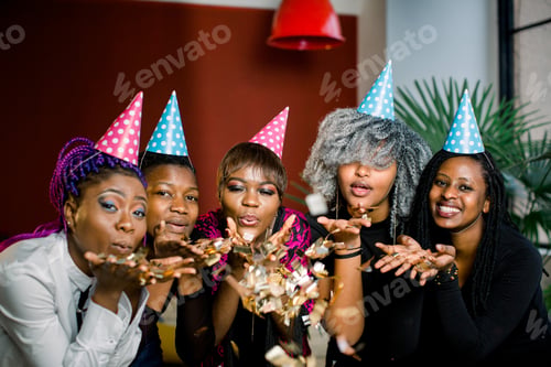 Preview: Confetti party. Happy young African group of people celebrating new year eve and blowing confetti