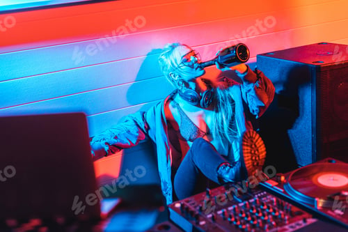 Preview: selective focus of attractive dj woman drinking wine from bottle with closed eyes
