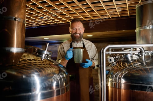 Preview: Smiling mature brewer holding plastic glass with granulated malt