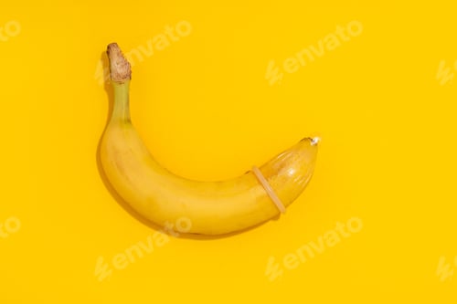 Preview: Banana with Condom on yellow background. Sexual Health and Education Concept