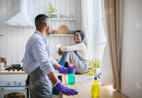 Preview: Young couple taking break during house cleanup, black man standing with detergent, girlfriend