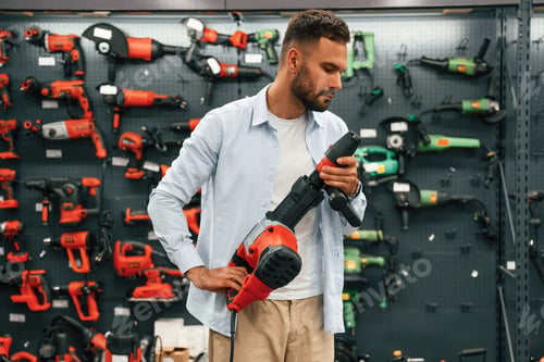 Preview: Plural perforator in hands. Man is in the hardware shop
