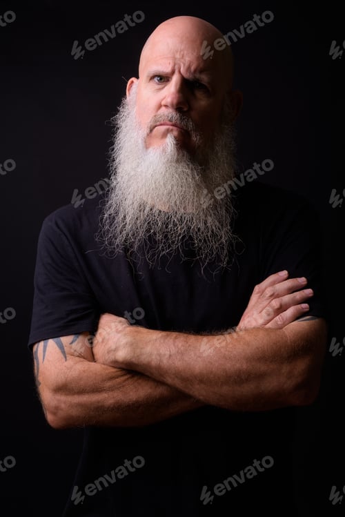 Preview: Mature bald bearded man against black background