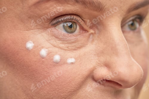Preview: Adult lady applying anti-aging cream to moisturize the skin