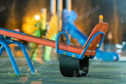 Preview: Seesaw swing in preschool yard with soft rubber flooring at night.
