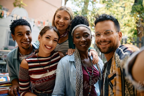 Preview: Multiracial group of friends having fun while taking selfie in a cafe and looking at camera.