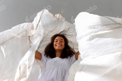 Preview: Overjoyed happy african american woman jumping with white fabric in air