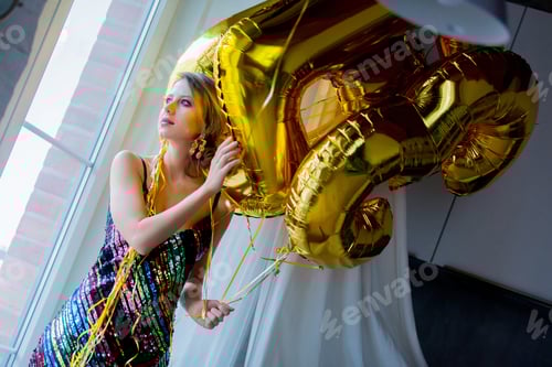 Preview: Young woman with golden balloons near window