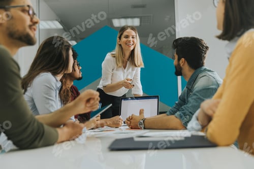 Preview: Pretty female team leader talking with mixed race group of people in the office