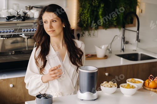 Preview: a girl makes a detox cocktail of fruit in the kitchen . Diet for weight loss