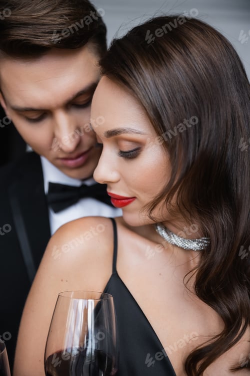Preview: Brunette woman with red lips standing near boyfriend and glass of wine at home