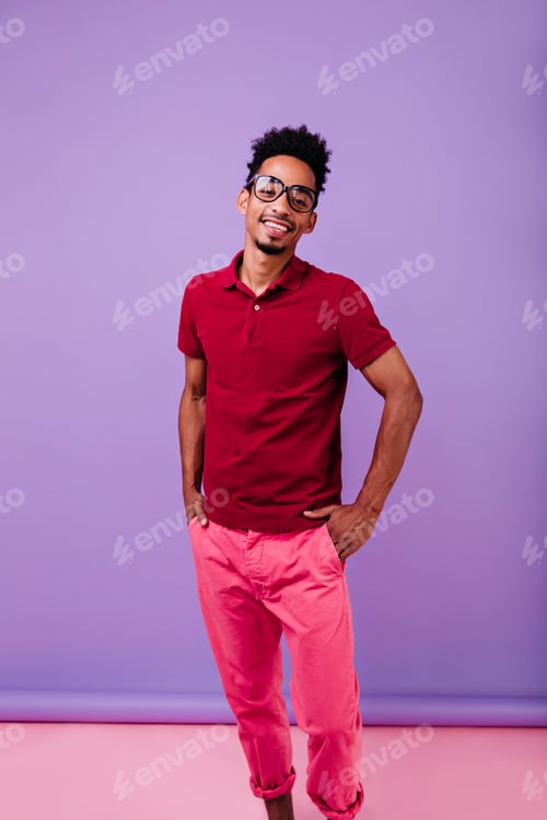 Preview: Happy black male model standing in confident pose. Smiling carefree man in pink pants and red t-shi