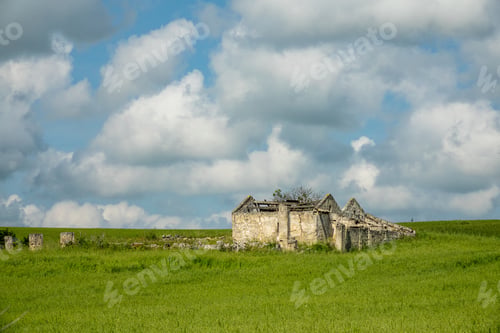 Preview: Building constructed on a green field under a sky full of clouds during daytime