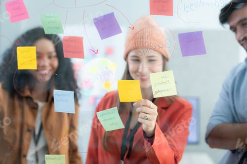 Preview: Multiethnic young business people brainstorming on a project by writing on the glass wall