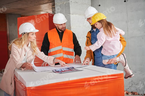 Preview: Family discussing building plan with builder at construction site.