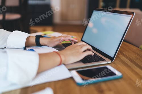 Preview: Unrecognizable woman browsing laptop at table