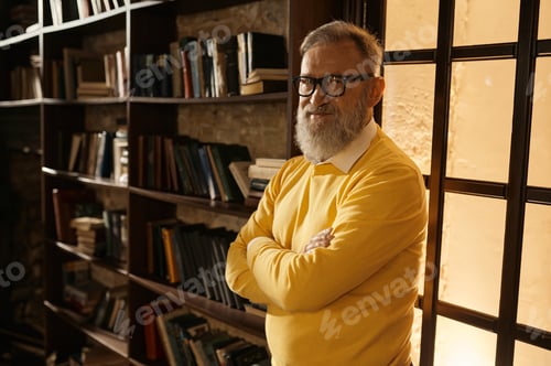 Preview: Pensive senior man standing with arms crossed on chest at home library