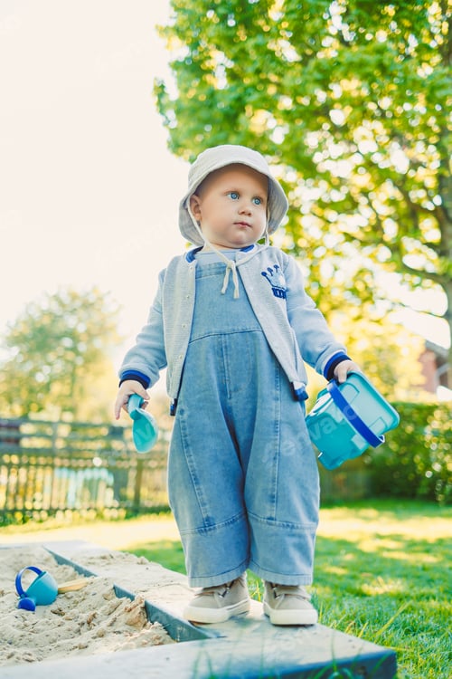 Preview: Toddler playing with a shovel in the sandbox on the playground. Boy playing in nature. 2 year old