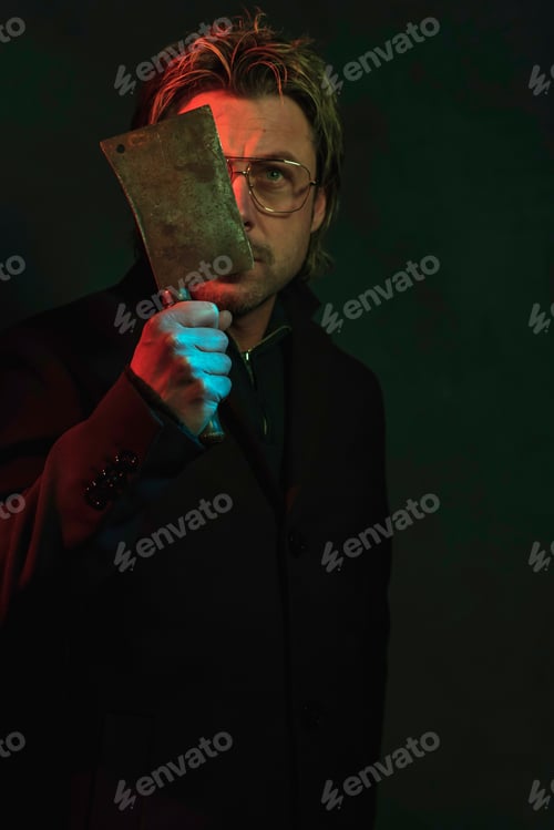 Preview: Man Holding Meat Cleaver Near His Face. Illuminated By Red And Green Light.