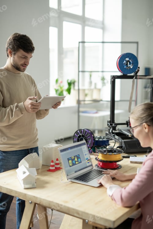 Preview: Young designer with tablet scrolling through online stuff by workplace