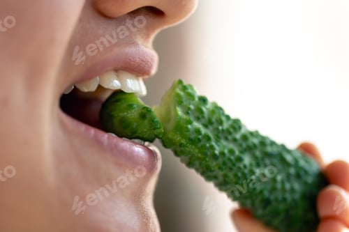 Preview: Detailed shot of a woman eats fresh cucumber.