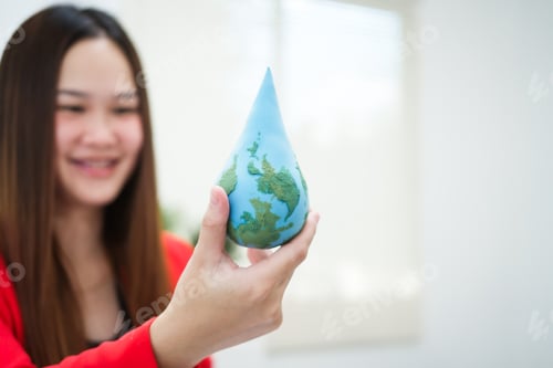 Preview: A young, smiling businesswoman holds a globe her desk, symbolizing global environmental awareness
