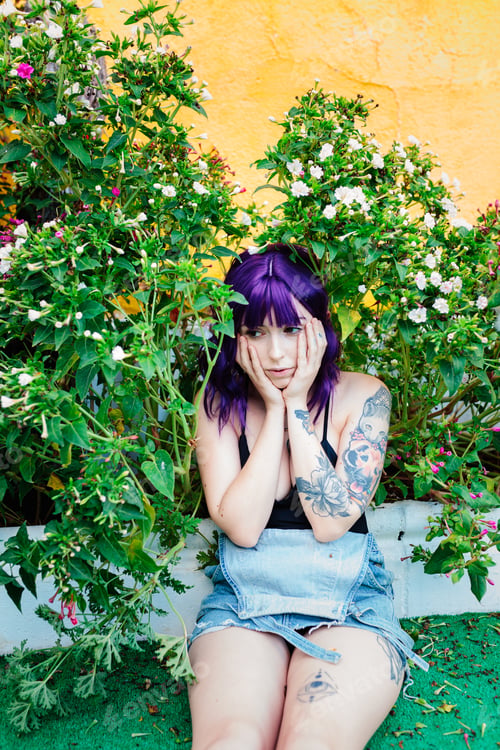Preview: Thoughtful woman sitting alone outdoors. Young worried in backyard