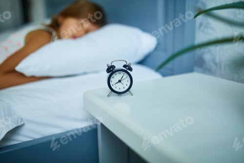 Preview: Little girl sleeping on a big and cozy bed white linen in the afternoon at home