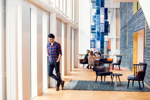 Preview: Young man walking through a modern atrium space with people in the background