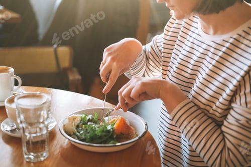 Preview: Young woman has healthy breakfast at table in morning cafe