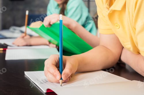Preview: Close-up partial view of schoolchildren writing with pencils